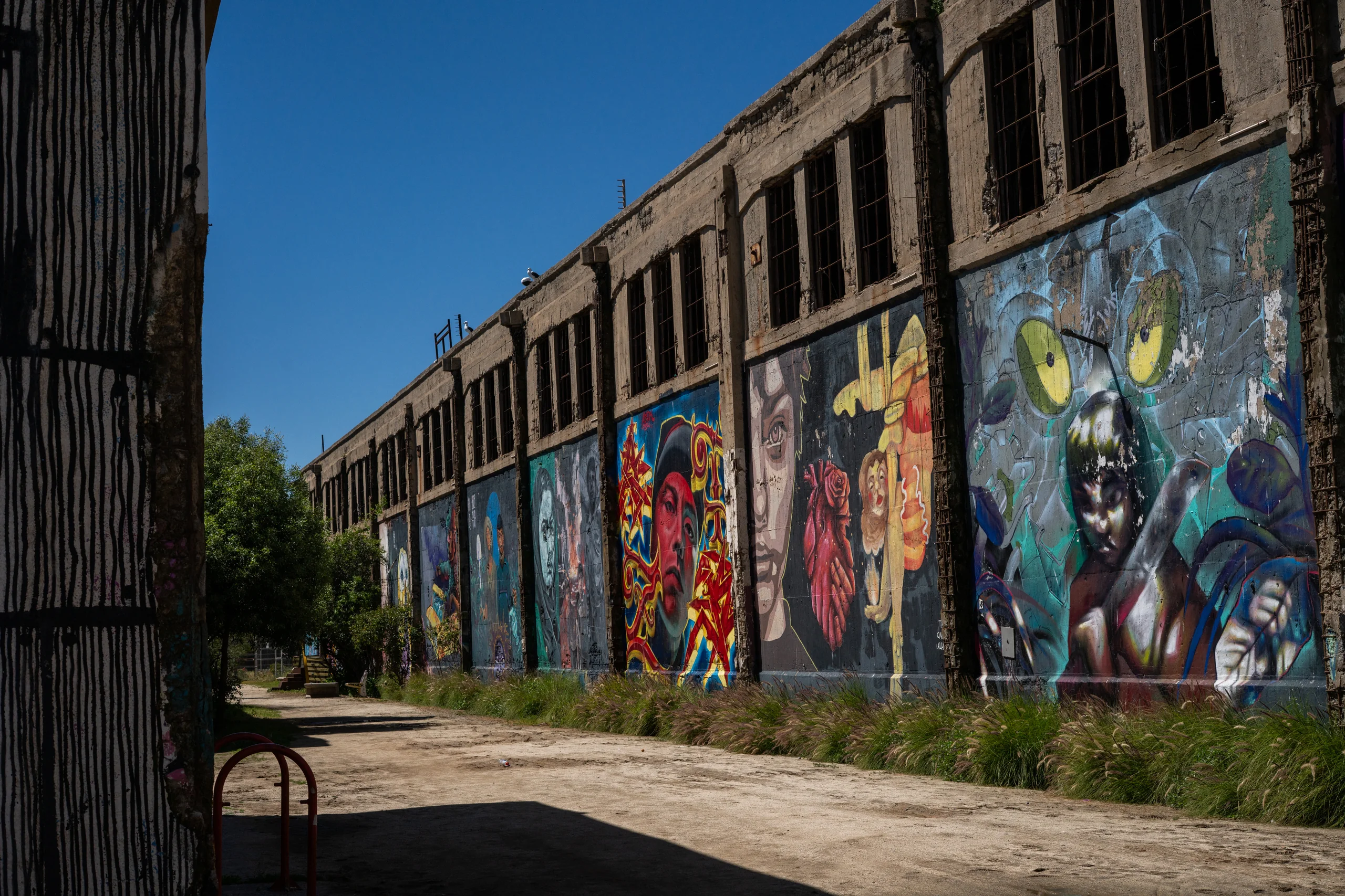 Murales y grafitis pegados a un edificio en ruinas, como si el arte lo mantuviera en pie un rato más.