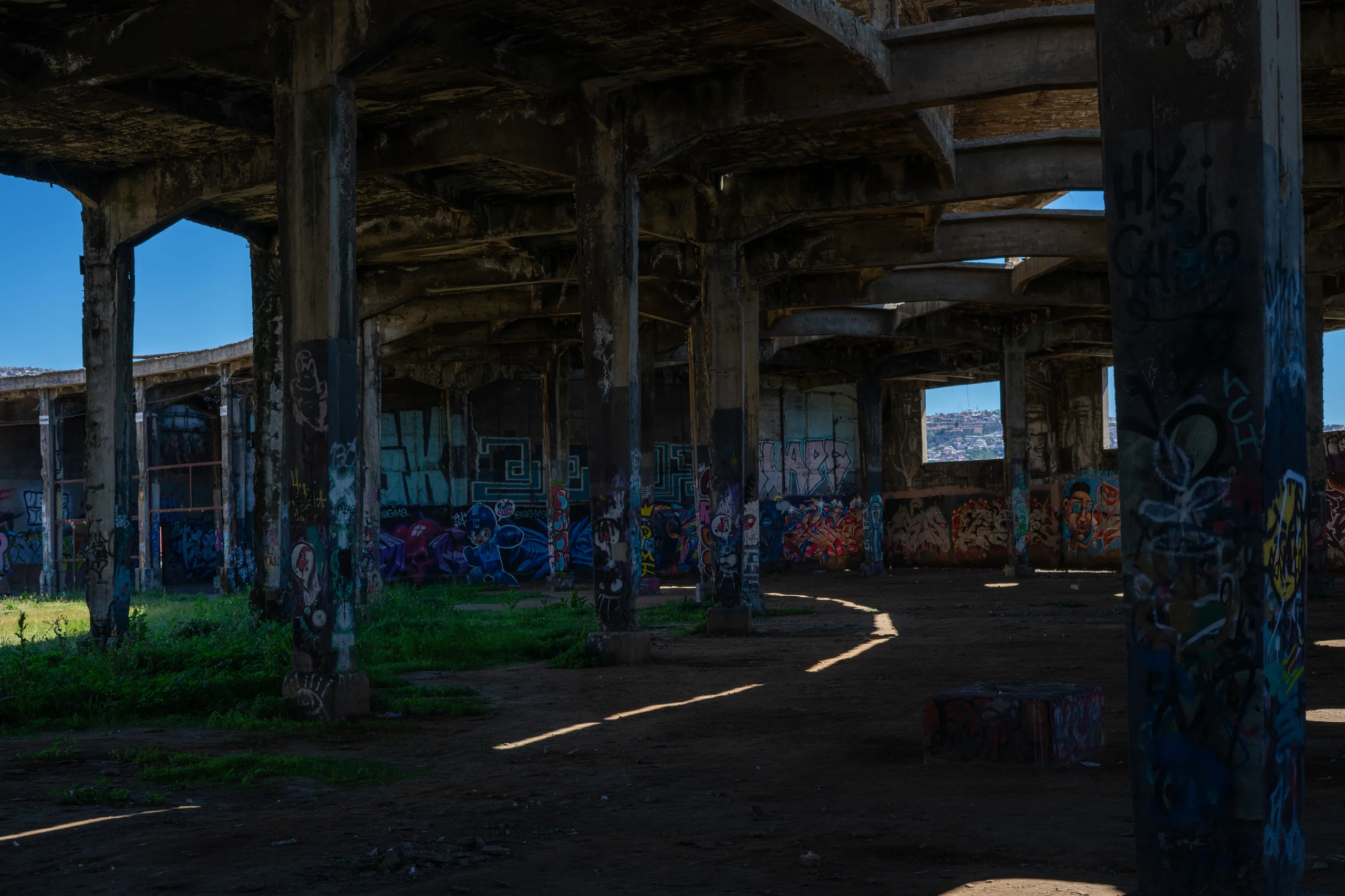 Interior de una construcción abandonada, columnas de concreto y grafitis por todos lados.