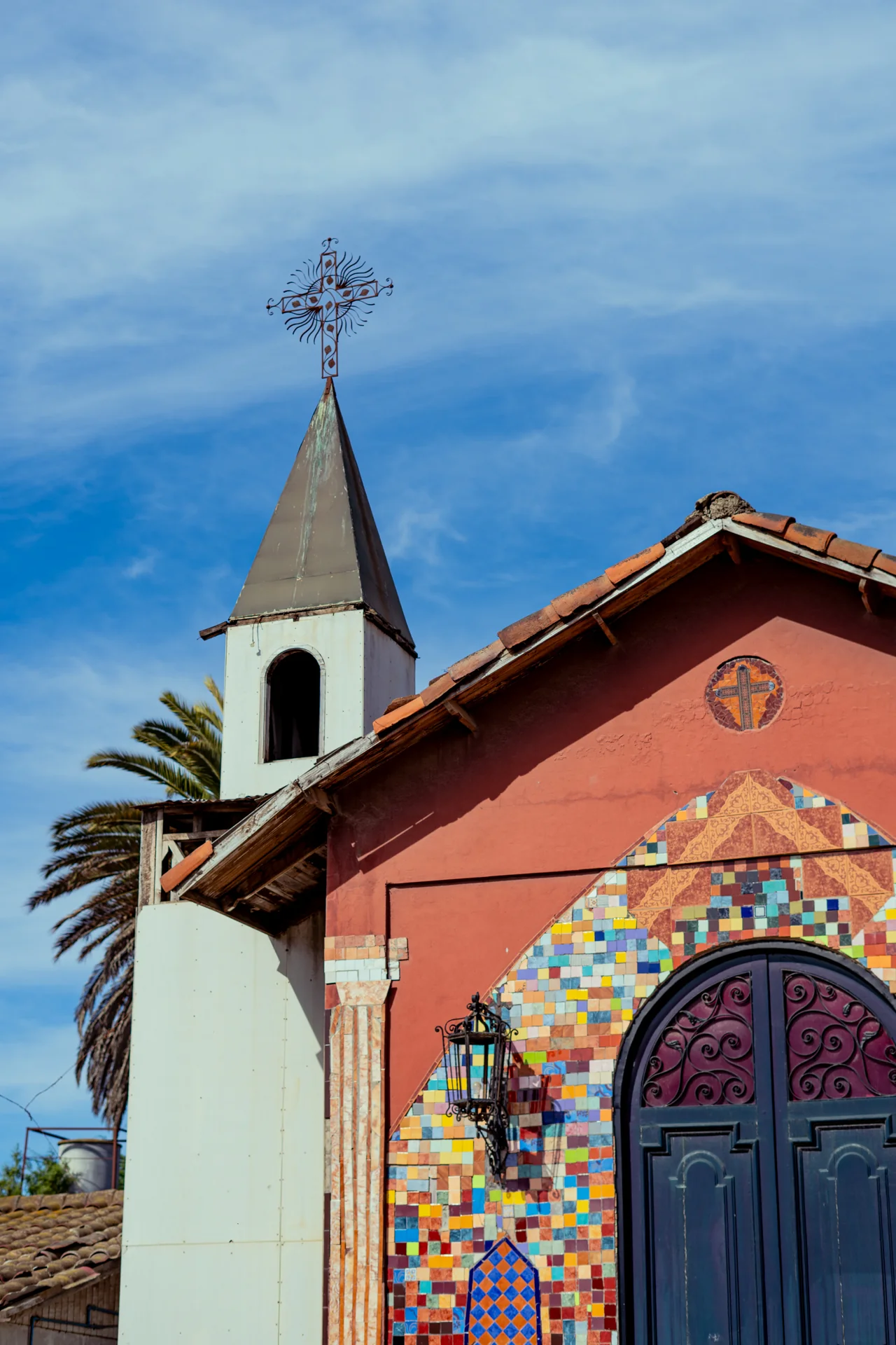Capilla de fachada colorida y cielo azul limpio, combinando fe, mosaico y costa.