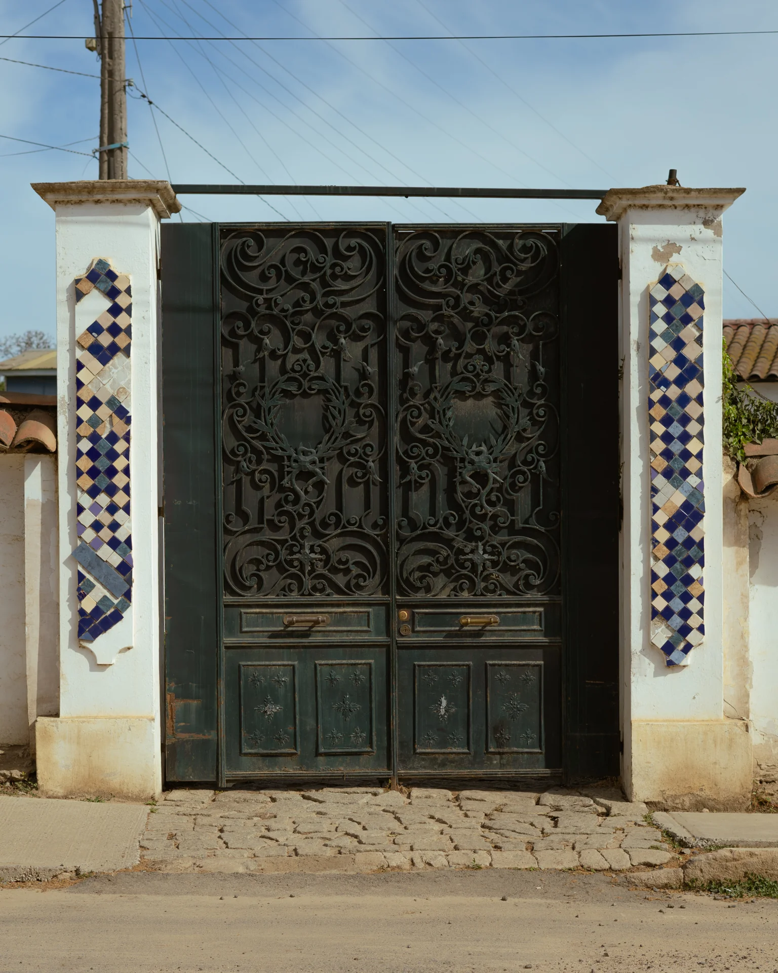 Puerta de metal trabajada y columnas con azulejos: detalle que uno podría pasar de largo si no bajara el ritmo.