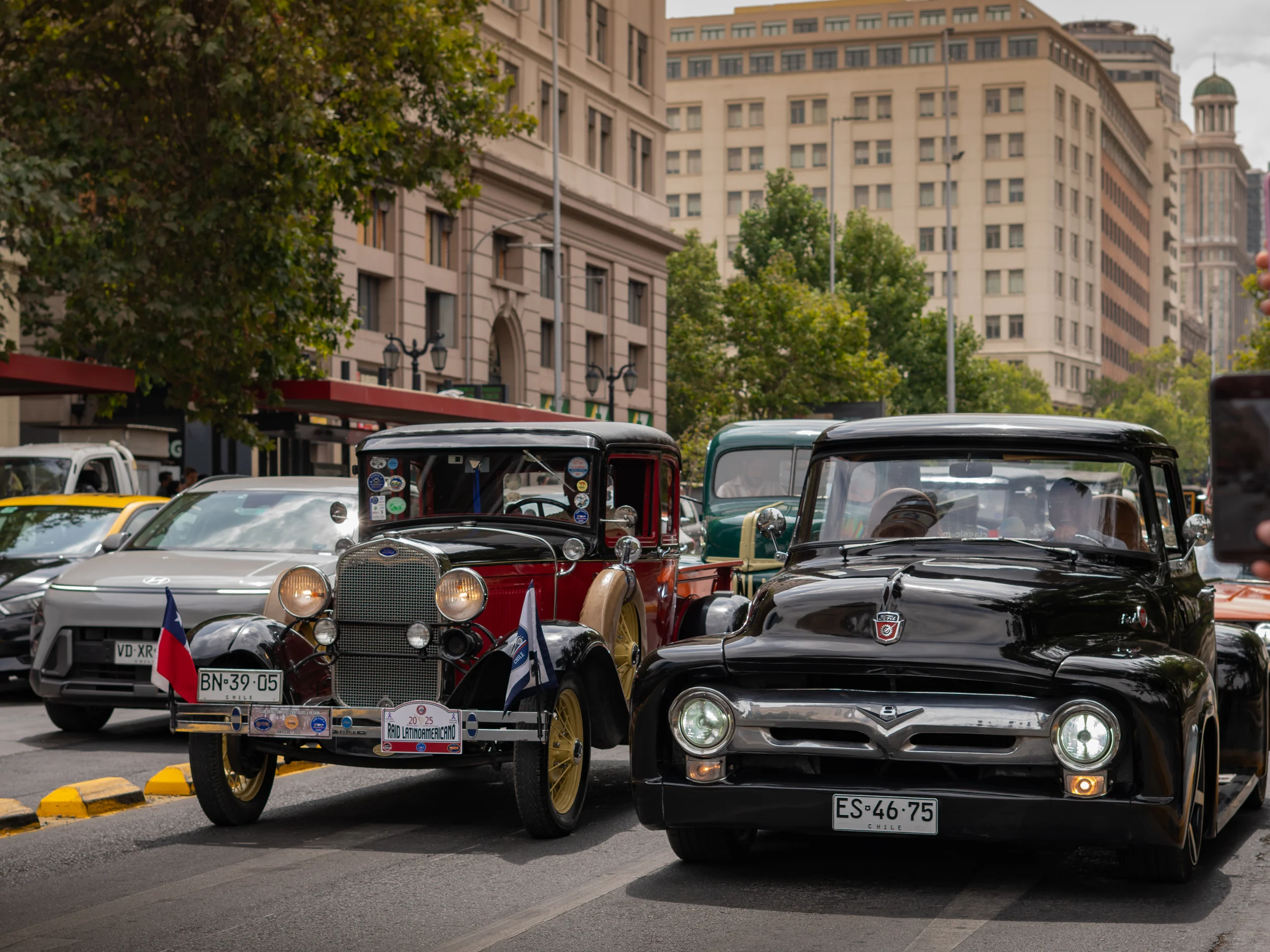 La imagen muestra una escena urbana en la que dos autos antiguos están detenidos uno al lado del otro en una calle.