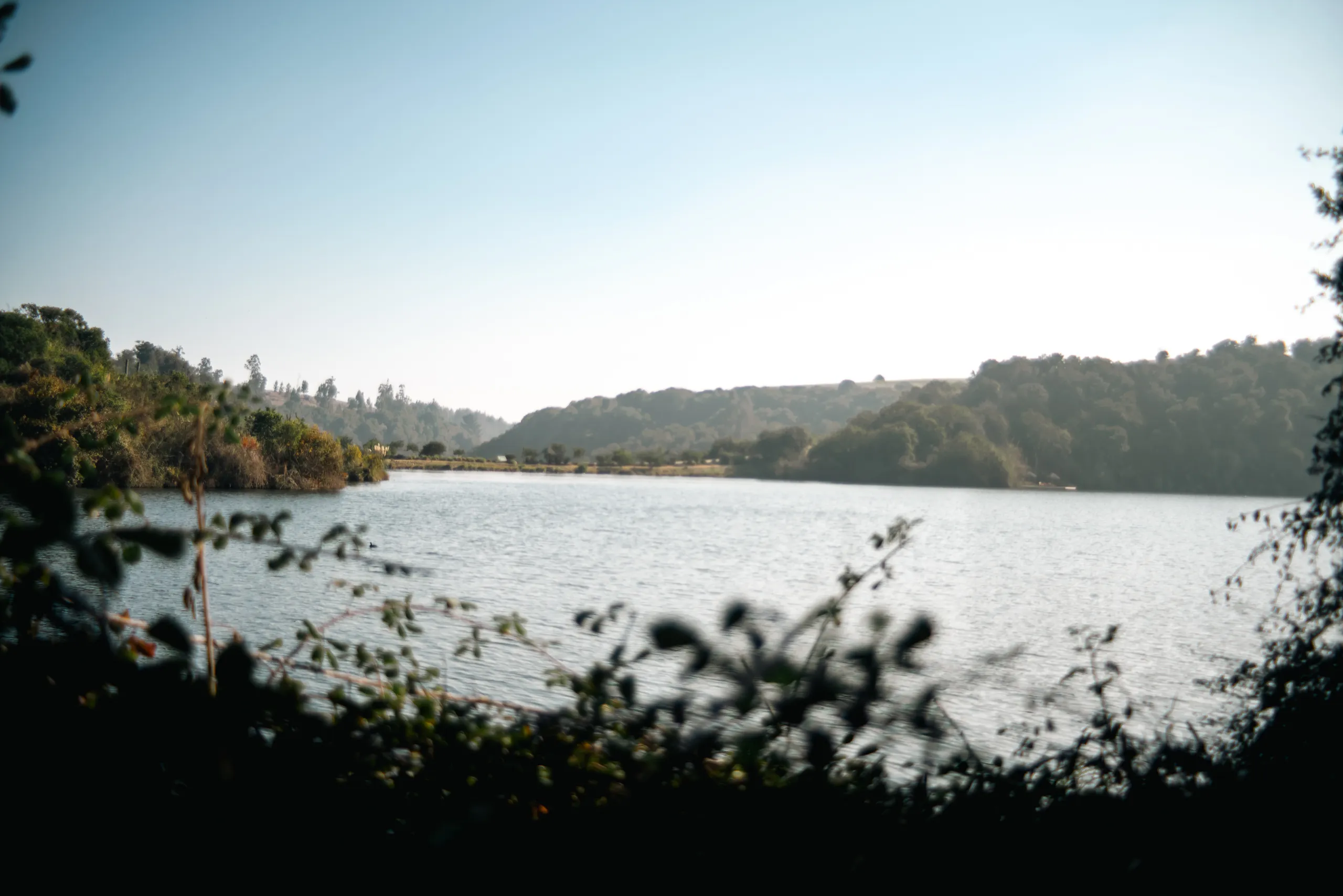Laguna tranquila rodeada de colinas y vegetación en el parque Tricao