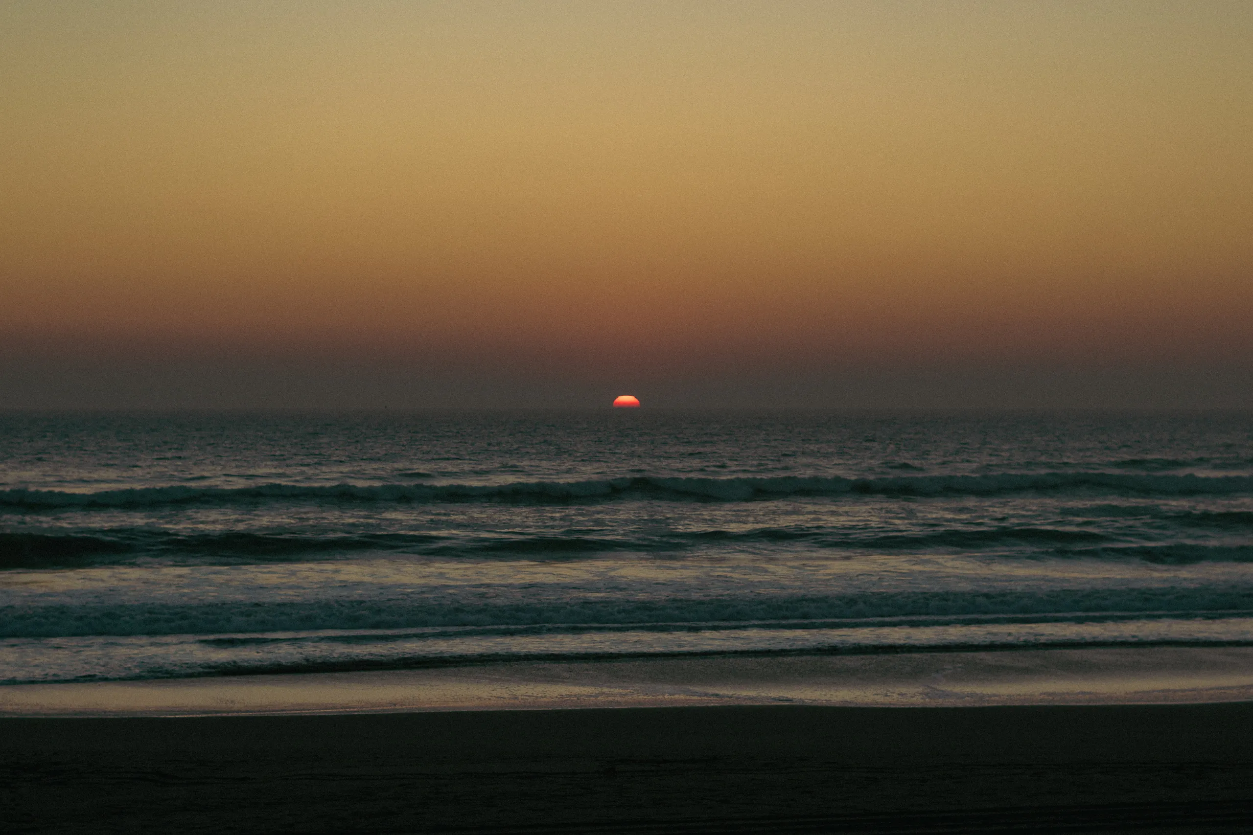 Último destello rojo del sol hundiéndose en el horizonte marino al anochecer